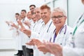 Smiling female doctor standing in front of her applauding colleagues. Royalty Free Stock Photo