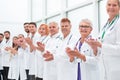 Smiling female doctor standing in front of her applauding colleagues. Royalty Free Stock Photo