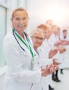 smiling female doctor standing in front of her applauding colleagues. Royalty Free Stock Photo