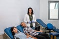 smiling female doctor standing next to two patients during blood transfusion