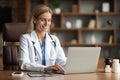 Smiling Female Doctor In Uniform Working With Laptop At Desk In Office Royalty Free Stock Photo