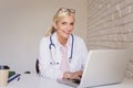 Smiling female doctor working on laptop at the doctor`s office Royalty Free Stock Photo