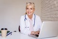 Smiling female doctor working on laptop at the doctor`s office Royalty Free Stock Photo