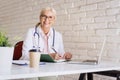 Smiling female doctor working on laptop at the doctor`s office Royalty Free Stock Photo