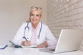 Smiling female doctor working on laptop at the doctor`s office Royalty Free Stock Photo