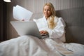 Pleased business lady with papers working on laptop in suite Royalty Free Stock Photo