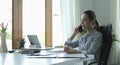 Smiling female entrepreneur sitting at bright modern office and talking on mobile phone Royalty Free Stock Photo