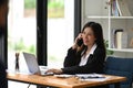 Female entrepreneur working with laptop and talking on mobile phone. Royalty Free Stock Photo