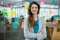 Smiling female executive standing with arms crossed in creative office Royalty Free Stock Photo