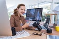 Smiling female executive using mobile phone while holding digital camera in office Royalty Free Stock Photo