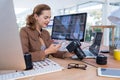 Female executive using mobile phone while looking at digital camera in office Royalty Free Stock Photo