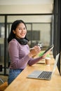 A smiling female freelancer remote working at the coffee shop, using her digital tablet Royalty Free Stock Photo