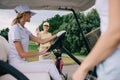 smiling female golf player greeting friend in golf cart