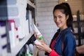 Smiling female hair dresser selecting shampoo from shelf at a salon Royalty Free Stock Photo