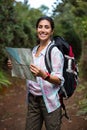 Smiling female hiker looking at map in forest Royalty Free Stock Photo