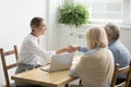 Smiling lawyer or financial advisor handshaking senior couple at Royalty Free Stock Photo