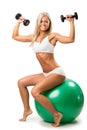 Smiling female lifting up a dumbbells seated on a fitness ball