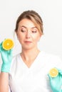 Smiling female nutritionist holding a sliced orange, looking at camera over white background, healthy diet concept. Royalty Free Stock Photo