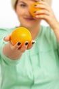 Smiling female nutritionist holding a whole orange, offering and looking at camera over white background, healthy diet Royalty Free Stock Photo