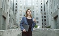 Smiling female office worker walking down the concrete stairs near business center holding coffee and laptop. Young cheerful Royalty Free Stock Photo