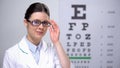 Smiling female optometrist adjusting glasses and looking to camera, professional