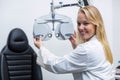 Smiling female optometrist adjusting phoropter