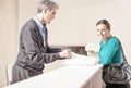 Smiling female patient in 40s received by male doctor at hospital reception desk Royalty Free Stock Photo