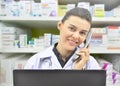 Smiling female Pharmacist Talking to Someone on Phone on pharmacy background Royalty Free Stock Photo