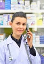 Smiling female Pharmacist Talking to Someone on Phone on pharmacy background Royalty Free Stock Photo