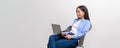 Smiling female professional doing online research over laptop on chair against white background