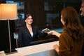 Smiling female receptionist taking passport from woman near man at desk in hotel Royalty Free Stock Photo