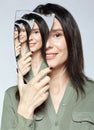 Smiling female with mirror shard in hand and multiple reflections