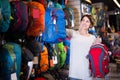 Smiling female shopper examining rucksacks in sports equipment store Royalty Free Stock Photo