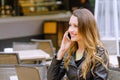 Smiling female speaking on smartphone in outdoors cafe