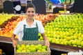 Smiling female staff holding a basket of green apple at supermarket Royalty Free Stock Photo