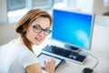 Smiling female student/ businesswoman using her tablet computer and a desktop computer