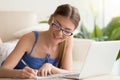 Lady writing in notebook when using laptop at home Royalty Free Stock Photo