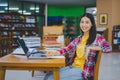 Smiling female student posing while working on laptop and searching for books to study, make report, find useful information in Royalty Free Stock Photo