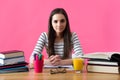 Smiling female student sitting at her desk filled with textbooks Royalty Free Stock Photo