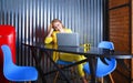 Smiling female student in yellow suit sitting at table and studding on laptop