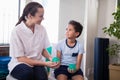 Smiling female therapist looking at boy holding stress balls Royalty Free Stock Photo