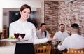 Smiling female waiter carrying order for visitors Royalty Free Stock Photo