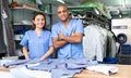 Smiling female worker of modern laundry standing with her colleague at reception counter, showing clean clothing and