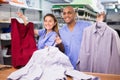 Smiling female worker of modern laundry standing with her colleague at reception counter, showing clean clothing and