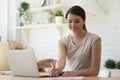 Smiling female working with laptop and making notes at kitchen Royalty Free Stock Photo