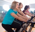 Smiling females riding stationary bicycles Royalty Free Stock Photo