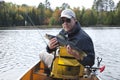 Smiling fisherman in a canoe on a northern Minnesota lake holds