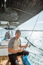 smiling fisherman holding a cell phone while fishing at sea