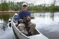 Smiling fisherman sitting in a canoe on a Minnesota lake holds up a walleye Royalty Free Stock Photo