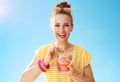 Smiling fit woman against blue sky drinking refreshing cocktail